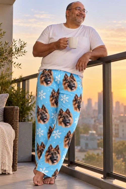 Man with coffee on a city balcony at sunset in blue snowflake pajama pants with German Shepherd faces