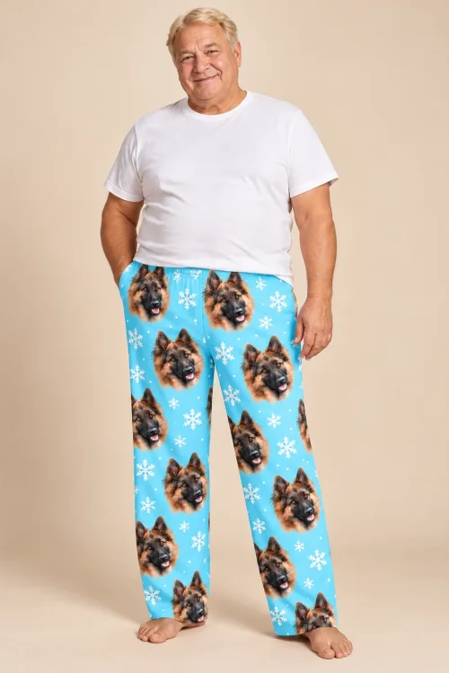 Smiling man in sky blue snowflake pajama pants with German Shepherd faces on a beige backdrop