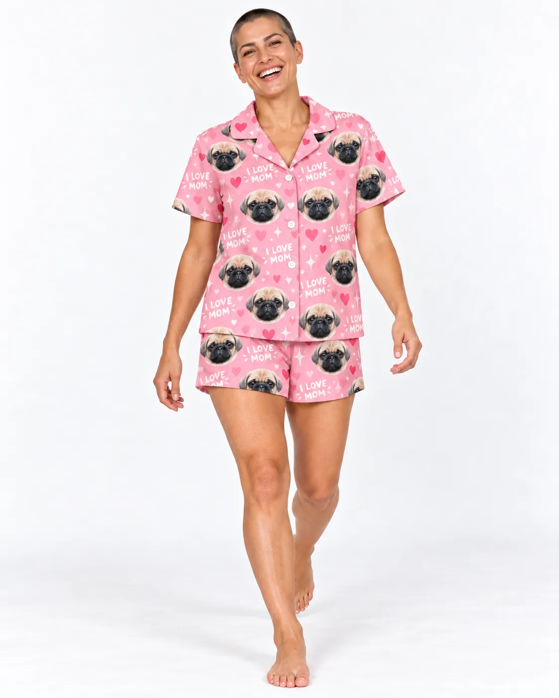 Smiling woman with a buzz cut walking in a pink mom pajama set with I LOVE MOM text and pug faces