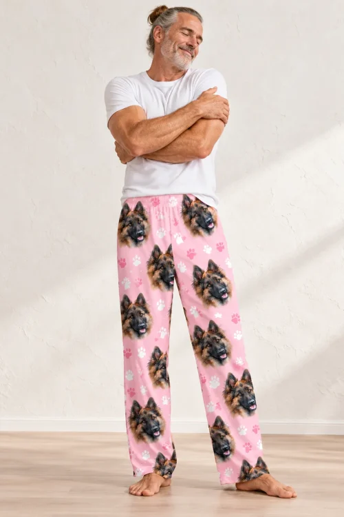 Gray-haired man hugging himself in blush pink paw print pajama pants with German Shepherd faces