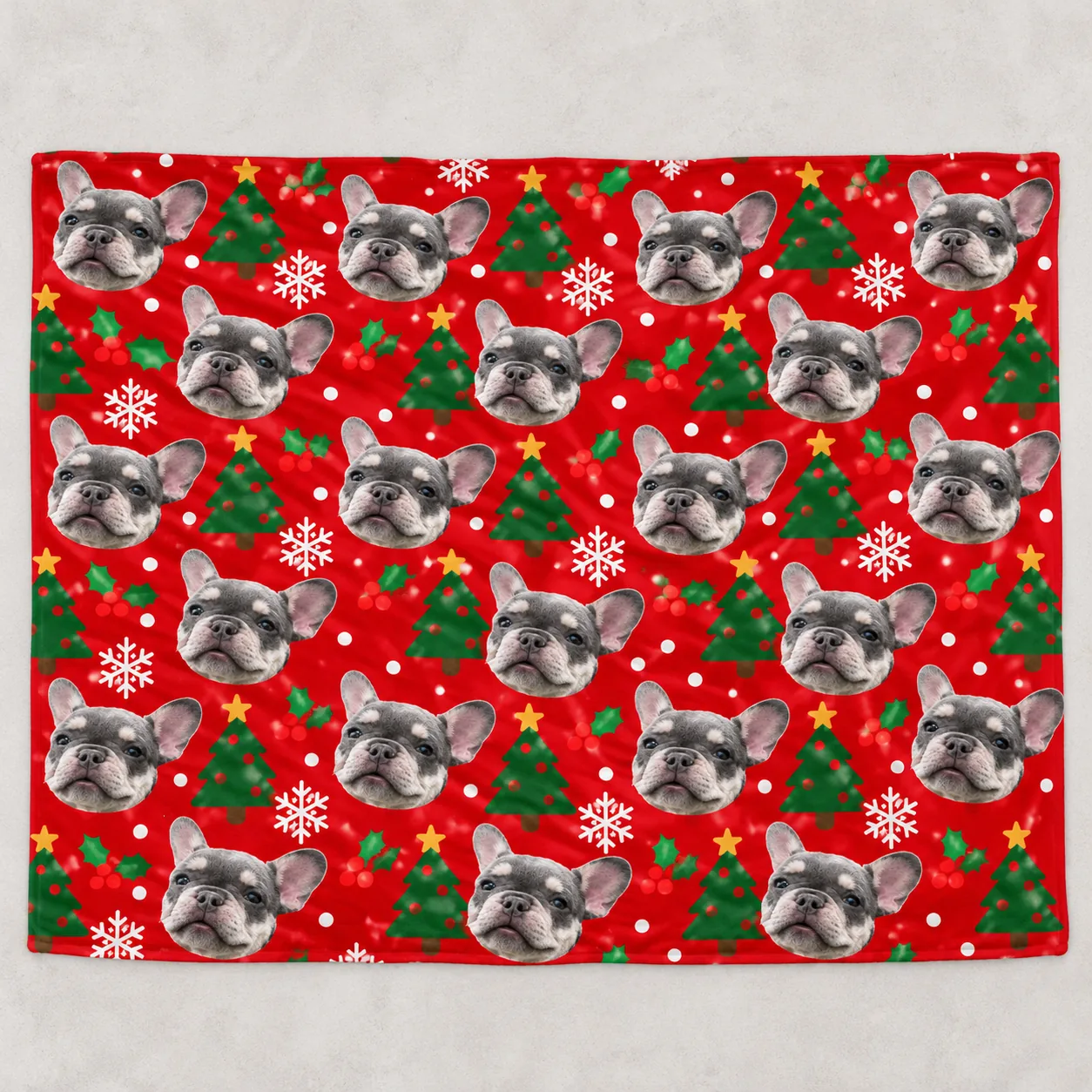 Personalized dog blanket in red fleece laid flat, printed with French bulldog faces and Christmas trees