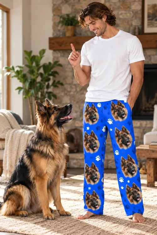 Man gives his German shepherd a command by the fireplace in royal blue paws pajama pants