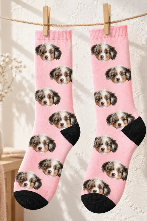 Pair of blush pink personalized socks with puppy faces hanging on a clothesline