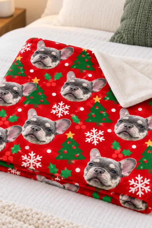 Folded pet face blanket on a bed, corner turned to show the white plush back
