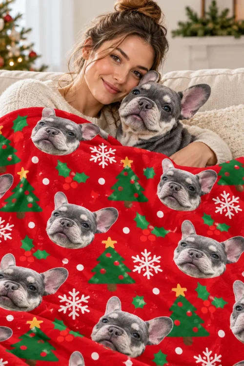 Woman and French bulldog cuddled under a pet face blanket on the sofa