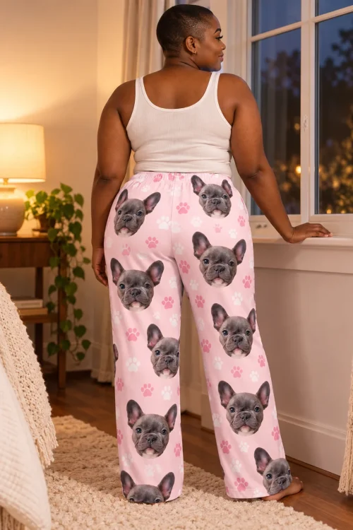 Back view of woman at an evening bedroom window in blush pink pajama pants with French bulldog faces and paw prints