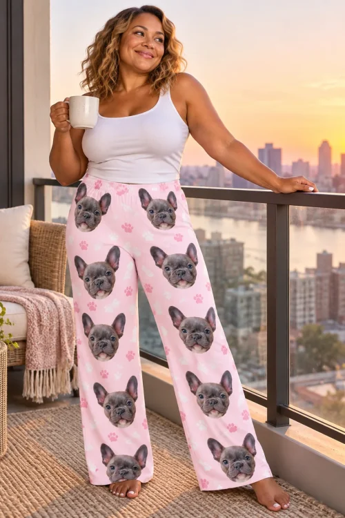 Woman with coffee on a sunset city balcony wearing blush pink paw print pajama pants with a grey French bulldog print