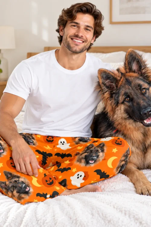 Man sitting on a bed beside his German shepherd in pet face pajama pants