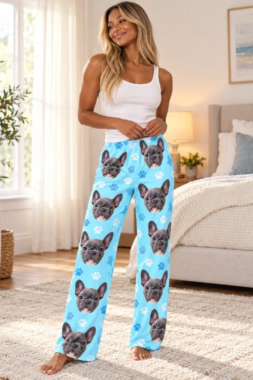 Woman in a sunny bedroom wearing light blue paw print pajama pants with a grey French bulldog face print, white tank