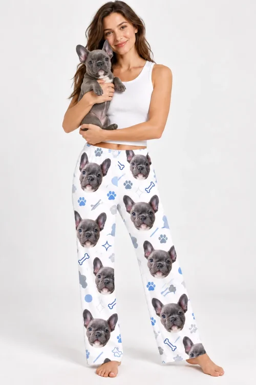 Woman holding her French bulldog, wearing pajama pants printed with its face