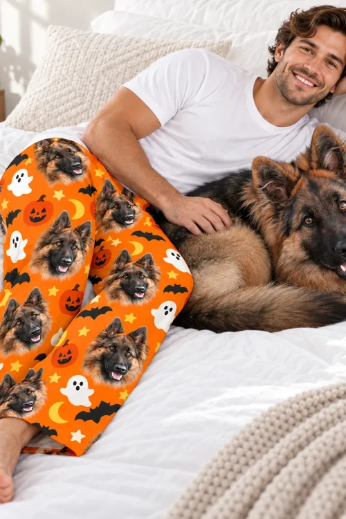 Man relaxing on a bed with his German shepherd, wearing pet face pajama pants of the same dog
