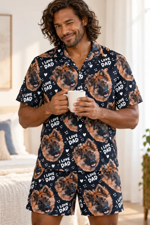 Winking man holding a mug in a sunny bedroom in a navy I Love Dad short pajama set printed with German shepherd faces
