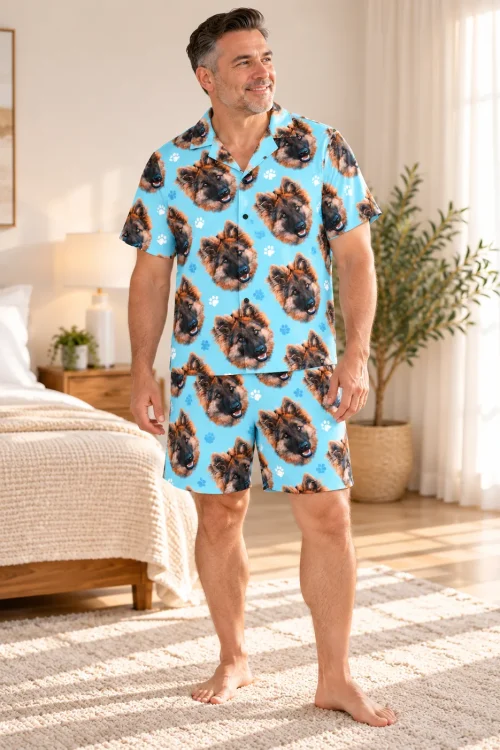 Smiling man standing in a sunny bedroom in a light blue paw print short pajama set printed with German shepherd faces