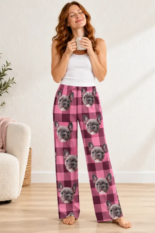 Woman with a mug and eyes closed in pink plaid pajama pants printed with French bulldog faces