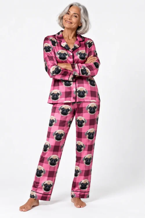 Silver-haired woman with arms crossed in a pink plaid pajama set printed with pug faces