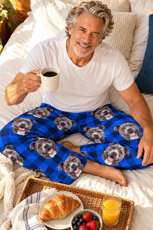 Man with coffee and a breakfast tray on the bed, wearing blue plaid pitbull pajamas for humans