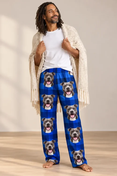 Man with locs wrapped in a cream knit shawl, wearing blue plaid pitbull pajama pants