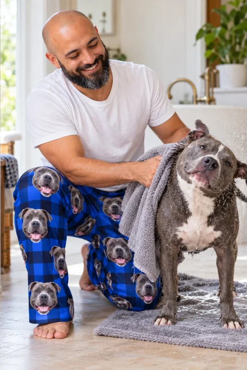 Man toweling off a wet pit bull on a bath mat, kneeling in blue plaid pitbull pajama pants