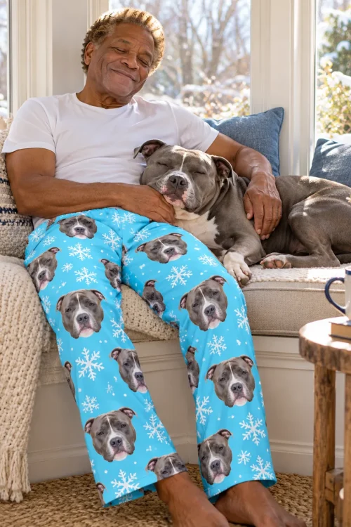 Man dozing in a sunny window seat with his pit bull, in light blue snowflake pitbull pajamas