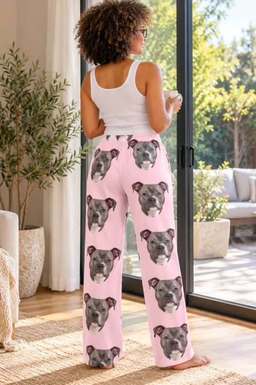 Back view of a woman with coffee at a patio door in blush pink pittie pajamas covered in pit bull faces