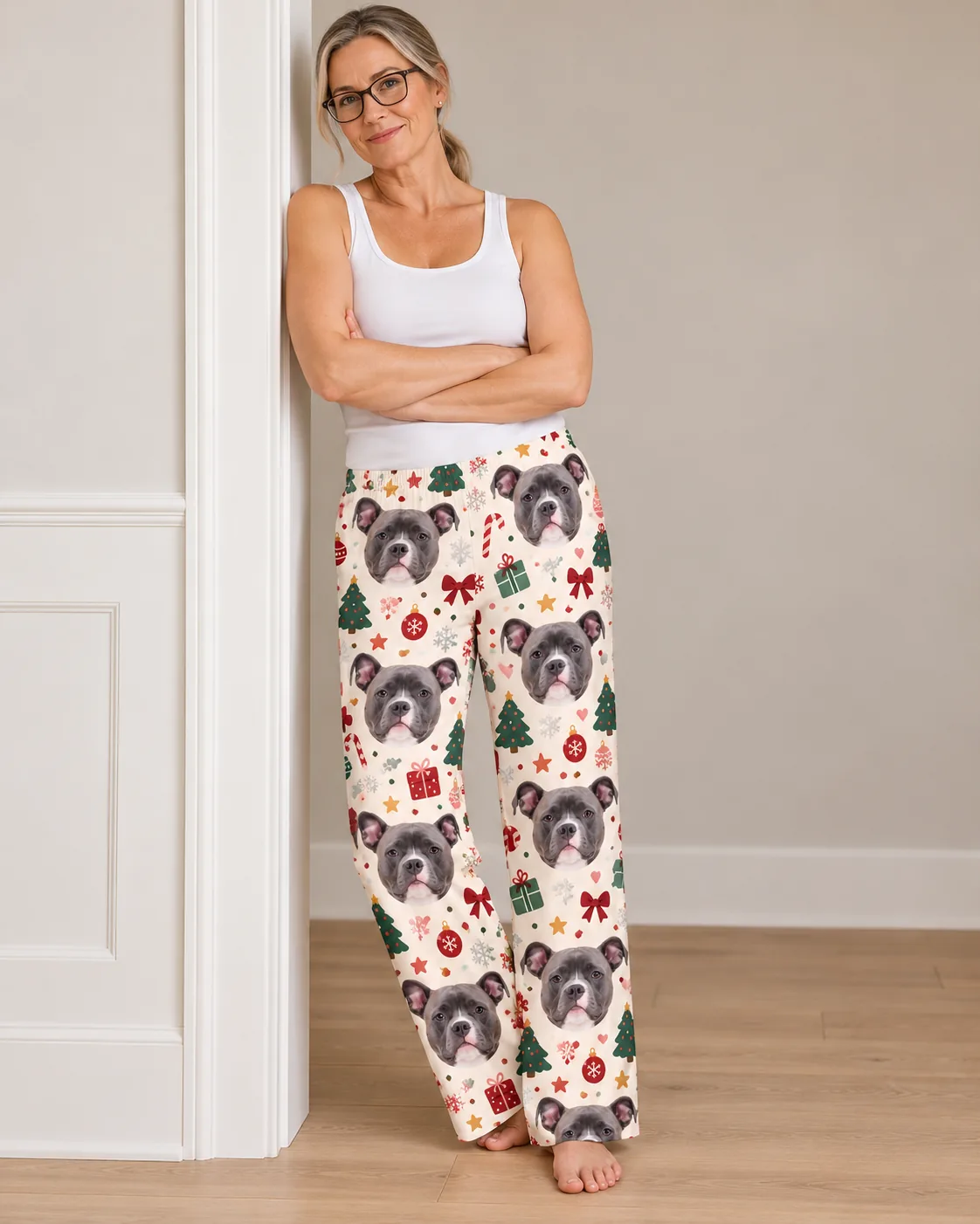 Custom Pitbull Pajama Pants for Women — christmas cream studio | GenzOutfit Woman in glasses leaning on a doorframe, arms crossed, in Christmas cream pittie pajamas with trees and bows