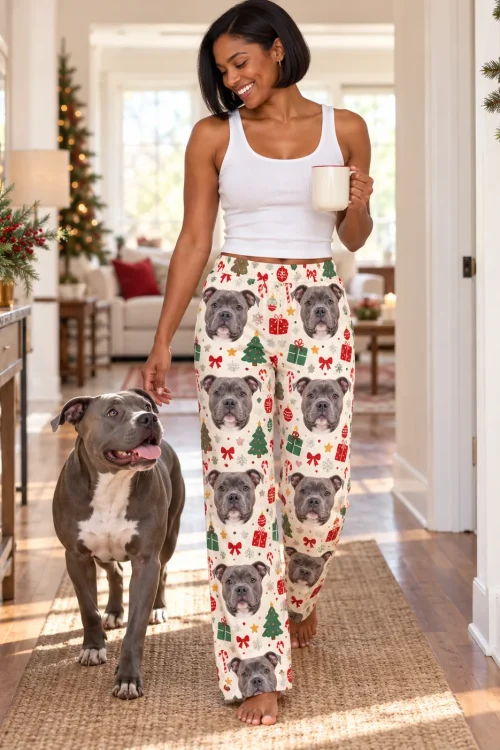 Woman with a mug walking her pit bull down a festive hallway in Christmas cream pittie pajamas