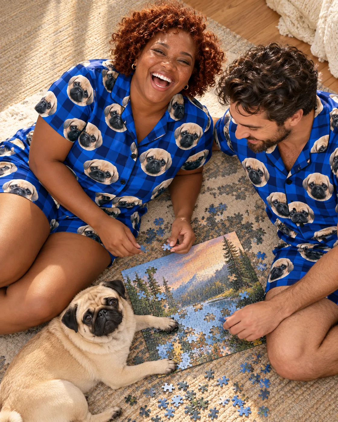 Plaid pajama pants: couple in blue plaid short sets with pug faces doing a puzzle beside their pug