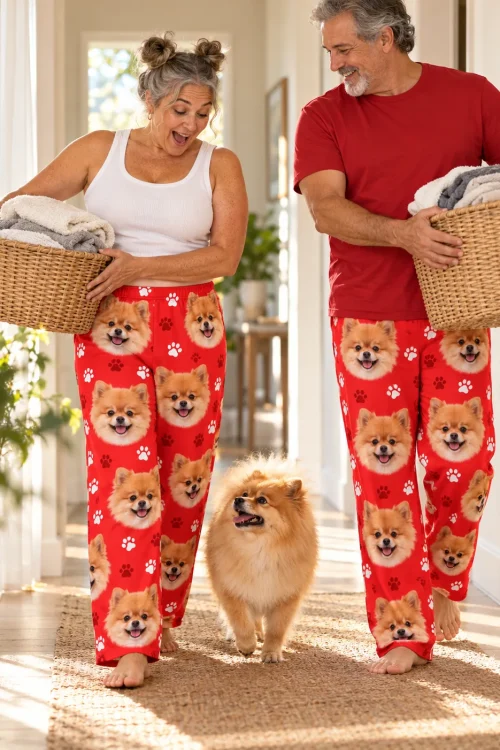 Couple carrying laundry baskets down a sunny hallway with their pomeranian, both in red paws pajama pants