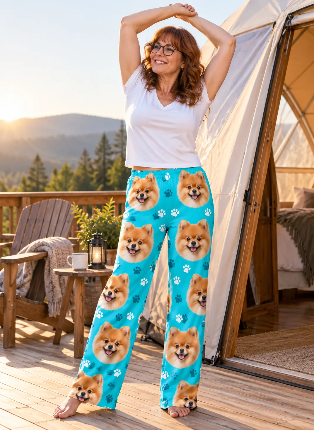 Woman in glasses stretching on a wooden glamping deck at sunrise, in teal paws pomeranian pajama pants