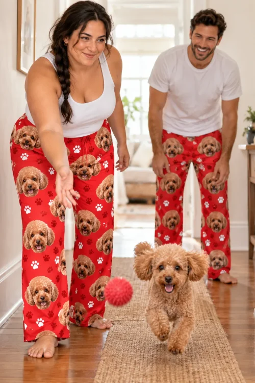 Couple in red paws poodle pajama pants tossing a ball to their poodle in a sunny hallway