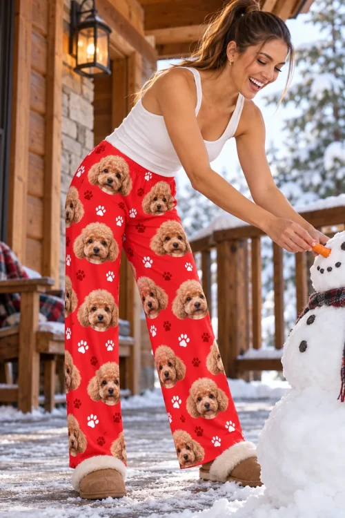 Woman giving a snowman a carrot nose on a cabin porch, in red paws poodle pajamas for women