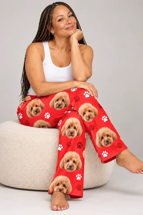 Woman with long braids sitting on a cream pouf in red paws poodle pajamas for women, gray studio