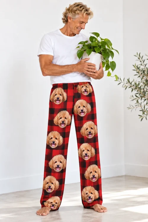 Man holding a potted plant, standing barefoot in red plaid poodle PJs with apricot poodle faces