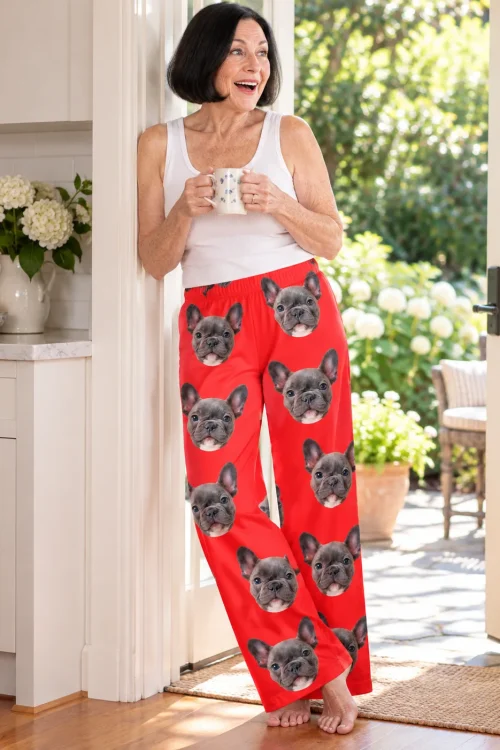 Smiling woman with a mug at an open garden door in red pajama pants with French bulldog faces