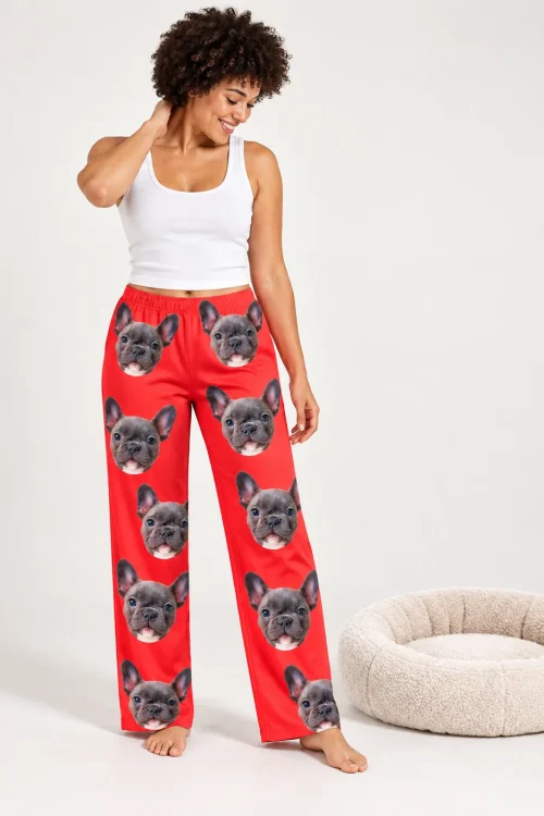 Woman with curly hair beside a dog bed in red pajama pants printed with French bulldog faces