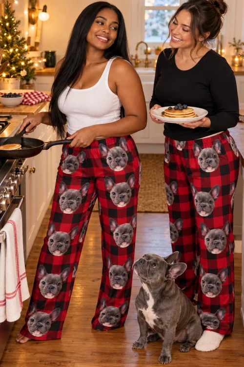 Two women making pancakes in a holiday kitchen in red plaid pajama pants, a French bulldog looking up