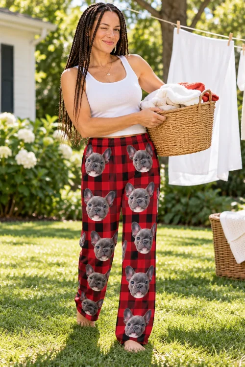 Woman with a laundry basket on a sunny lawn in red plaid pajama pants printed with French bulldog faces