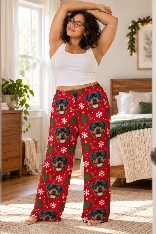 Woman stretching in a sunny bedroom in red Christmas pajama pants printed with Rottweiler faces and snowflakes
