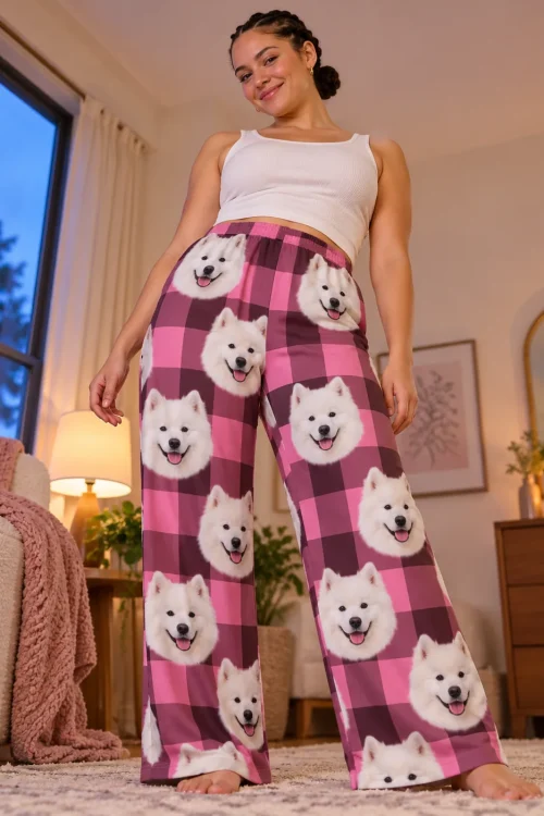 Low-angle view of a woman in a candlelit bedroom wearing wide pink plaid pajama pants printed with samoyed faces