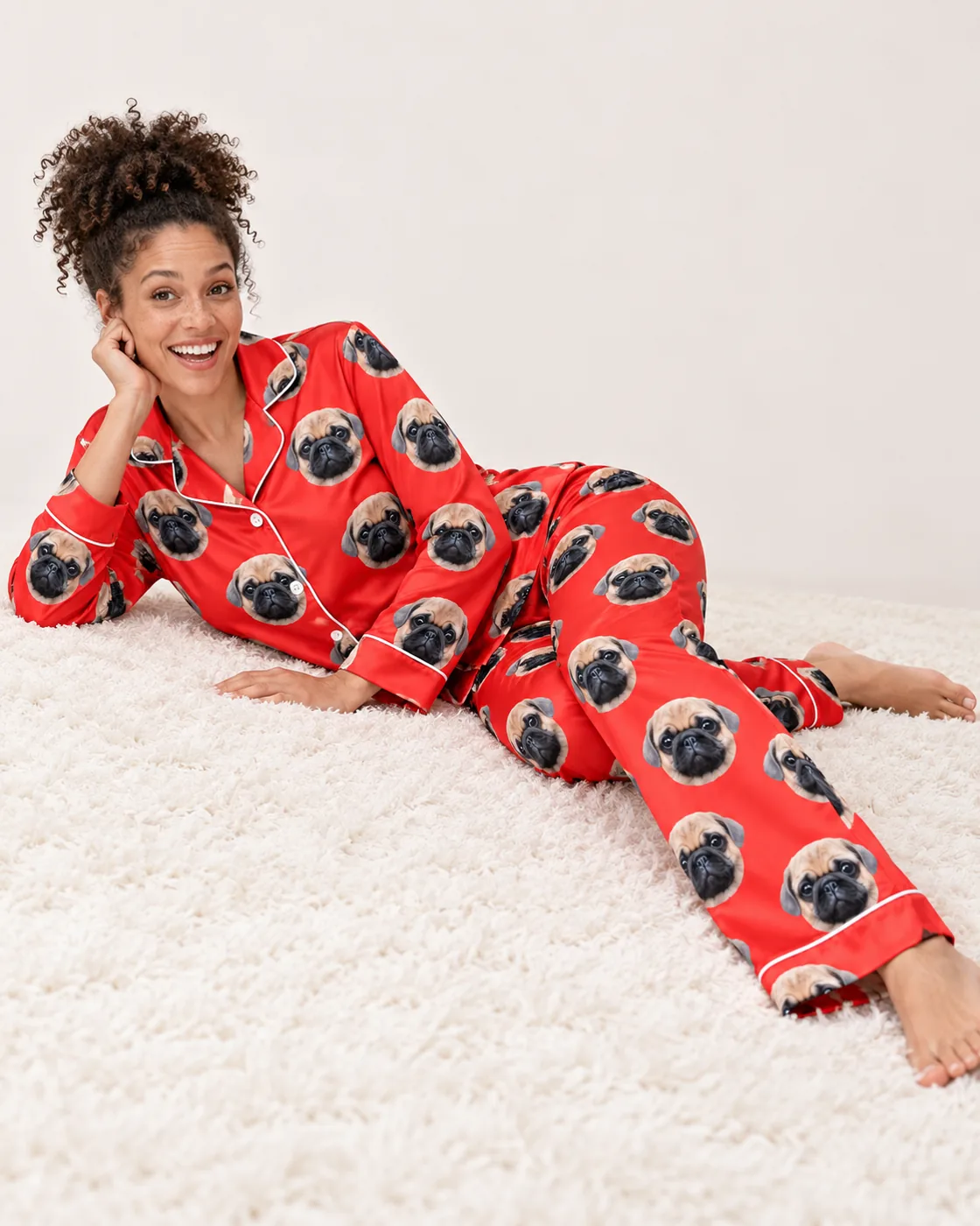 Satin pajamas for women: woman lounging on a rug in a red satin set printed with pug faces