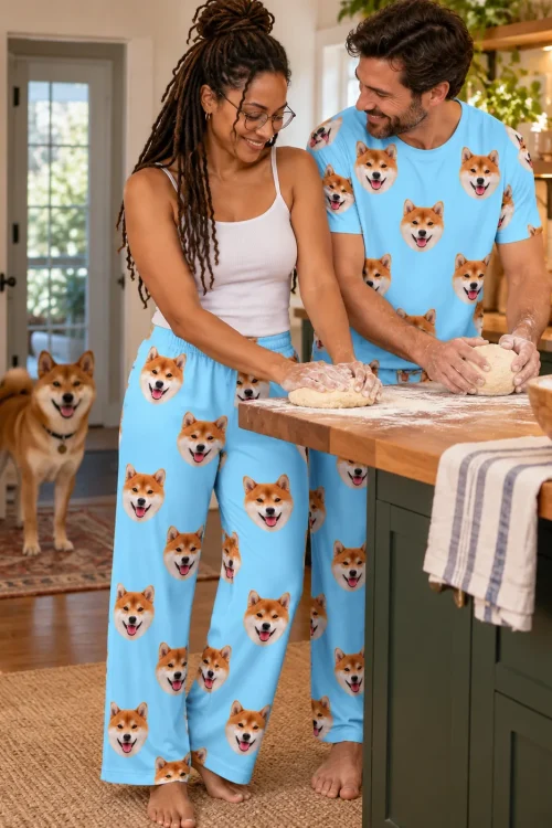 Couple kneading dough in a kitchen in light blue shiba inu pajama pants while their shiba watches from the doorway
