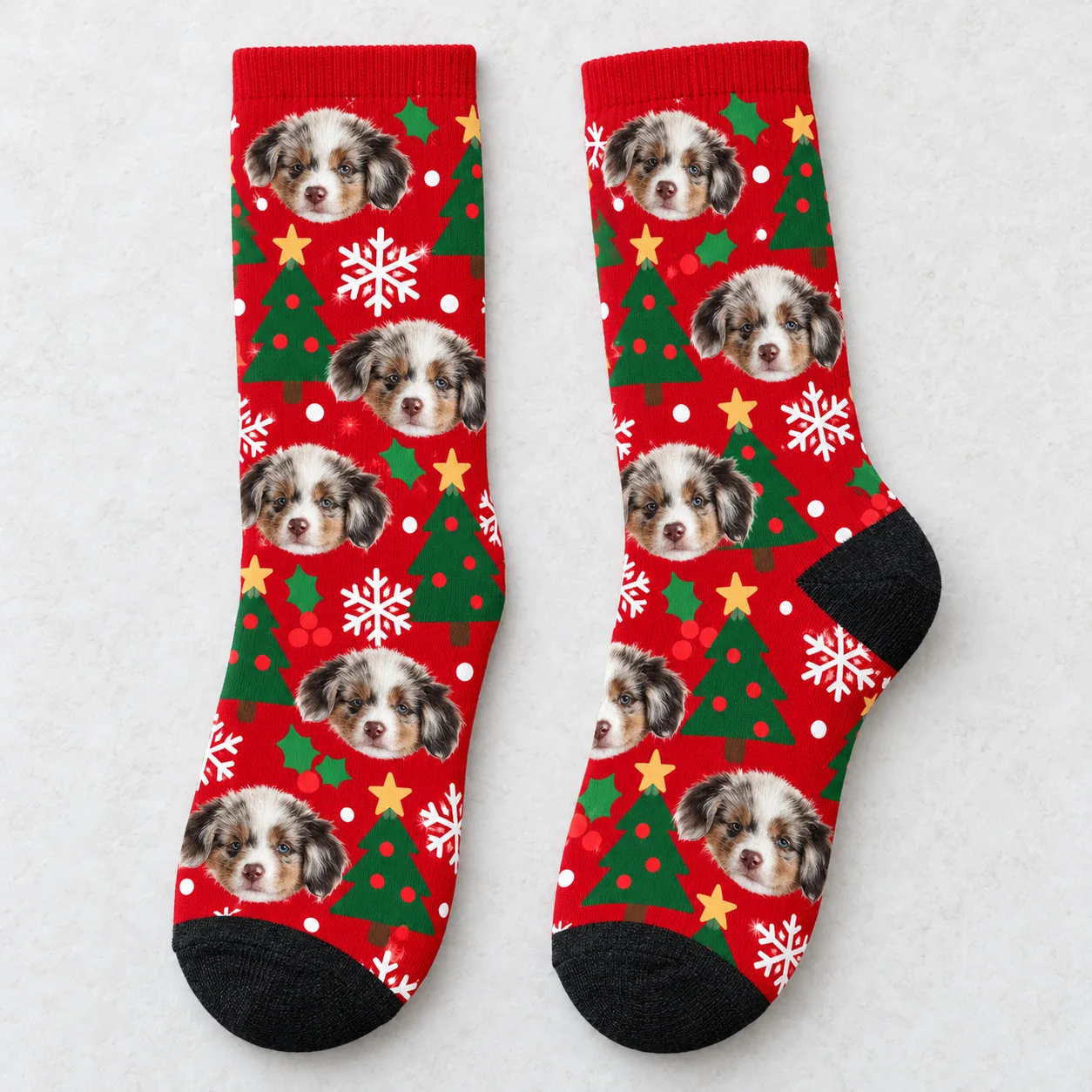 Pair of red Christmas crew socks with puppy faces, trees and snowflakes laid flat