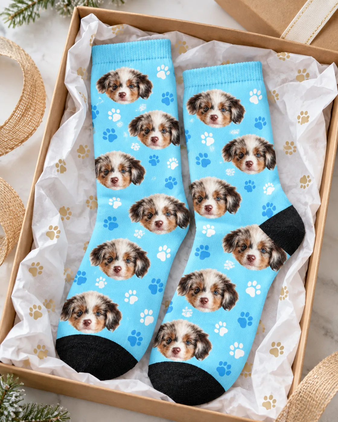 Light blue paw print socks with puppy faces in a gift box with tissue paper