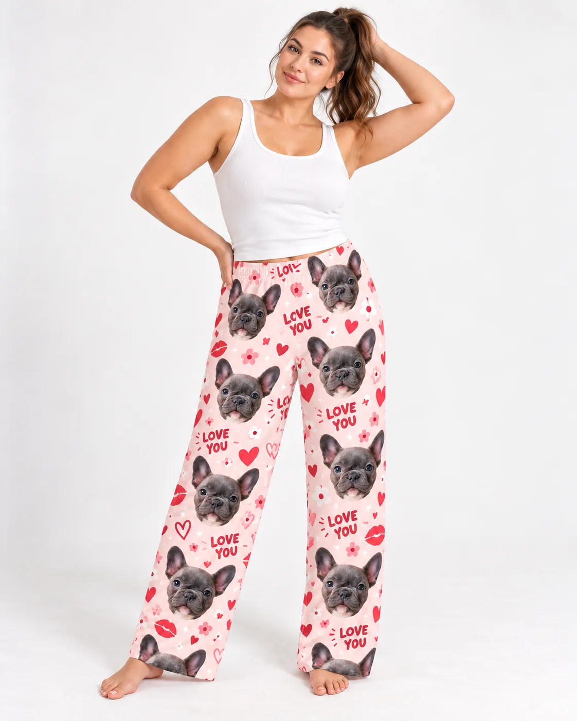 Woman with a hand in her hair in pink valentine pajama pants with French bulldog faces and hearts