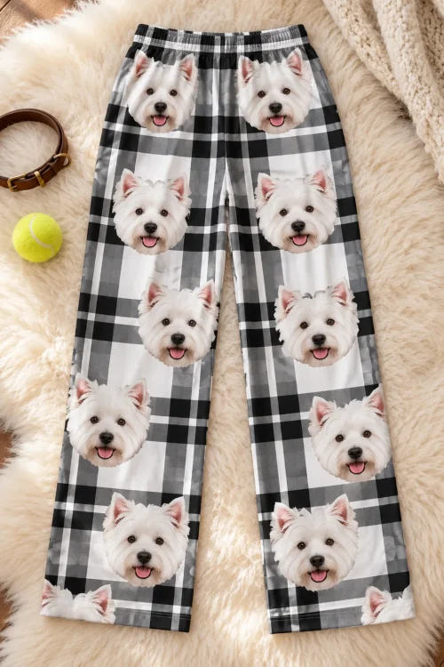 Black and white plaid Westie pajamas laid flat on a fluffy rug with a leather dog collar and a tennis ball