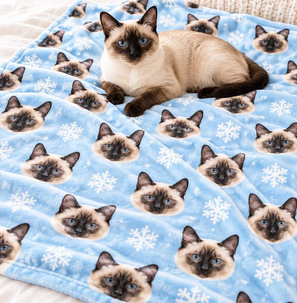 Siamese cat lying on a light blue snowflake photo blanket printed with Siamese cat faces
