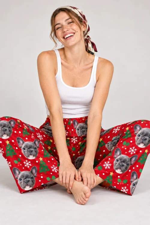 Woman in a headscarf sitting cross-legged in red Christmas pajama pants with French bulldog faces