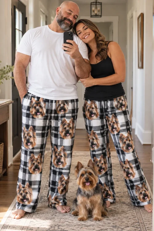 Couple taking a hallway mirror selfie in white plaid Yorkshire terrier pajama pants, their Yorkie sitting in front